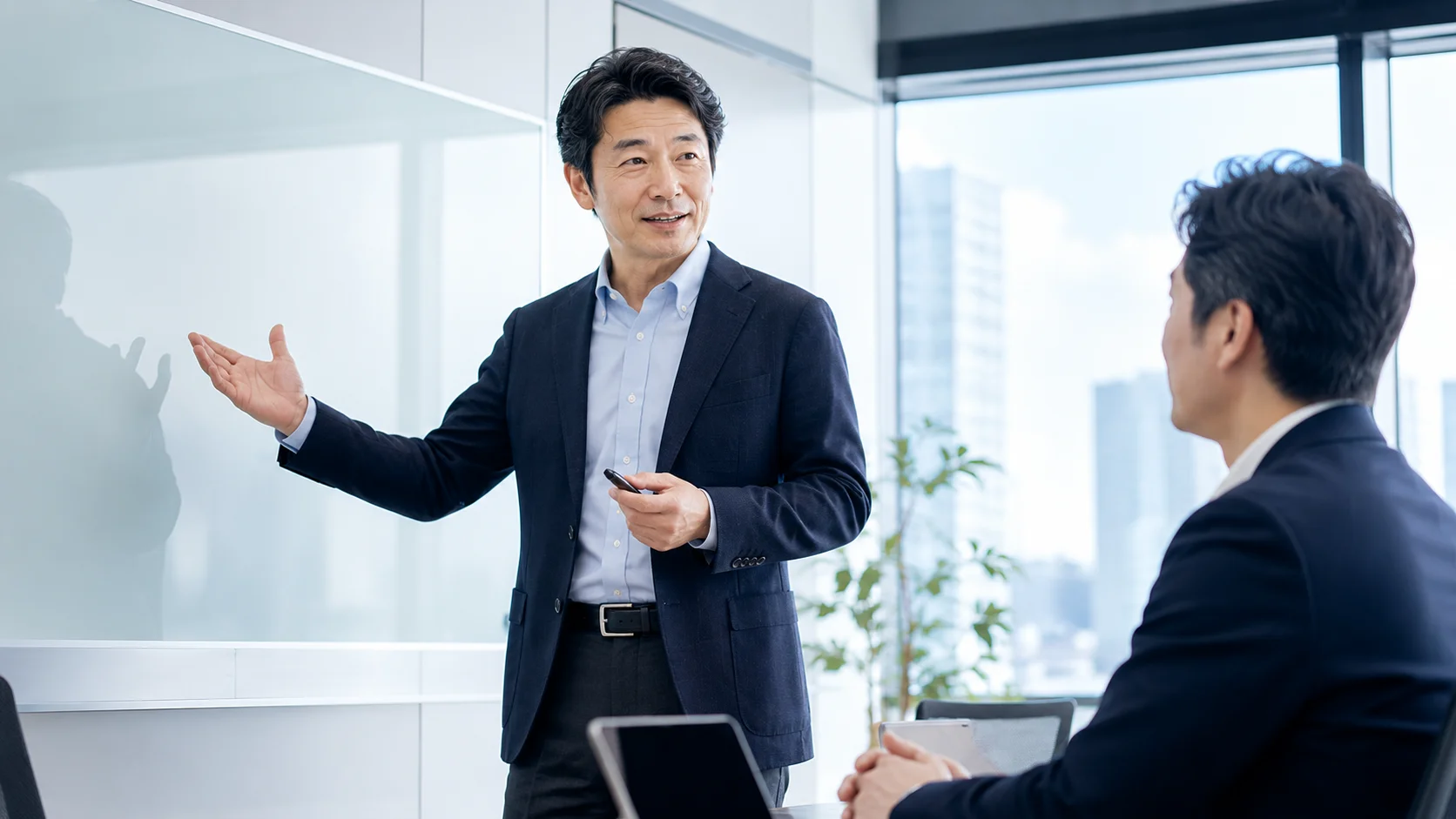 IT業界のM&Aと事業承継の基礎を会議室で説明する日本人ビジネスパーソン