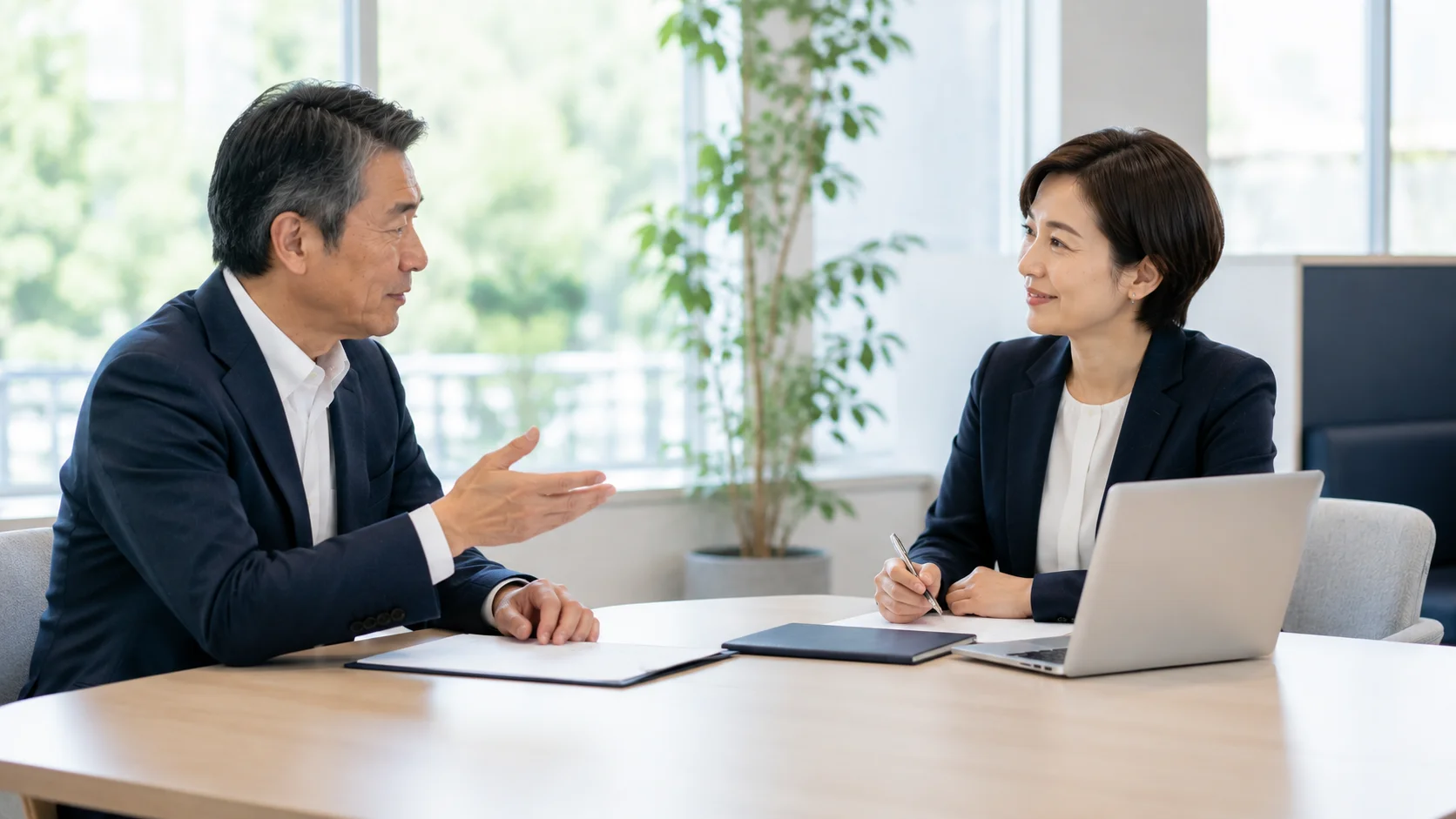 テーブル越しに穏やかに質問する日本人経営者とアドバイザー。M&Aの価格に関する疑問を相談するイメージ