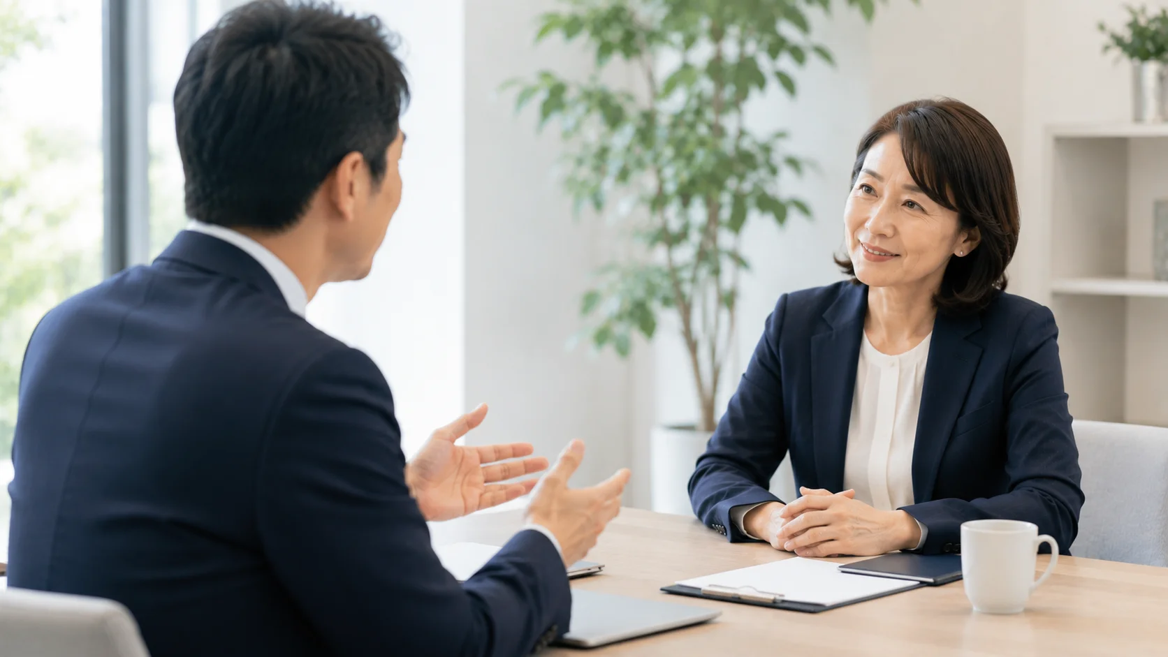 デスク越しに穏やかに質問へ答える日本人の専門家と経営者。M&Aの失敗に関するよくある疑問を解消するイメージ